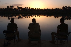 two guys sitting near pond